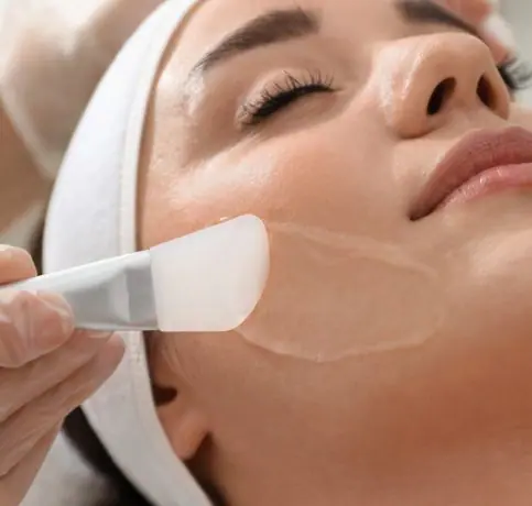 Woman getting a facial with a peel being applied to her face